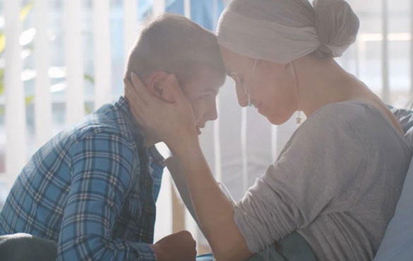 A mother in a hospital bed cradles her young son's face