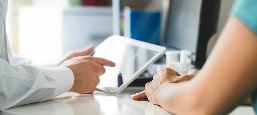 A pharmacist and a customer gathered around a tablet