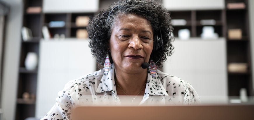 A woman sitting in front of a computer with a headset on