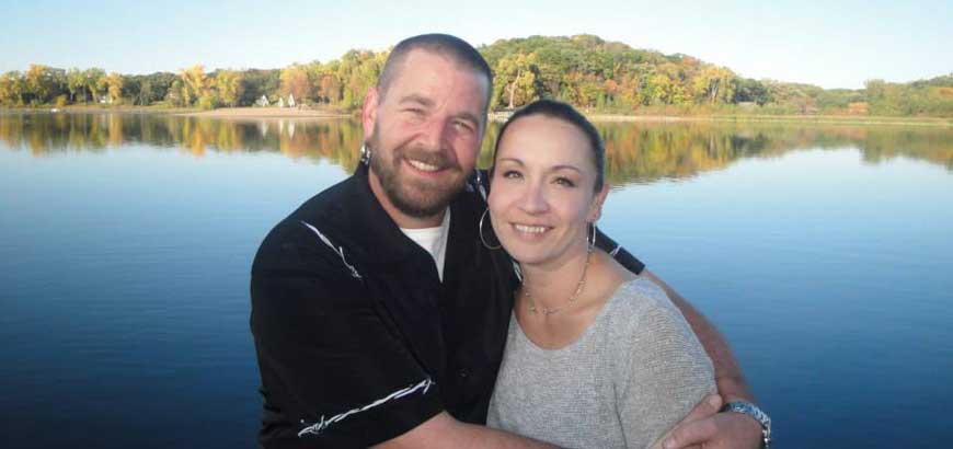 Becky and her husband embrace each other while standing by Lake Superior