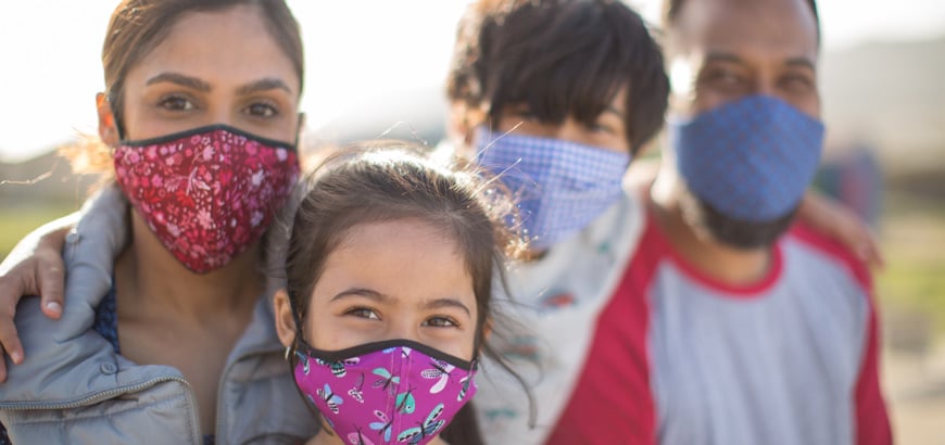 <span>A family wearing masks looking at the camera</span>