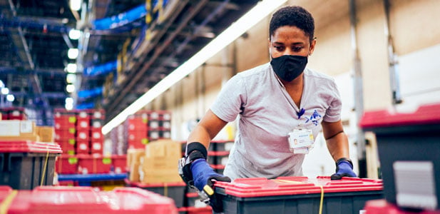 An employee packs crates in a warehouse