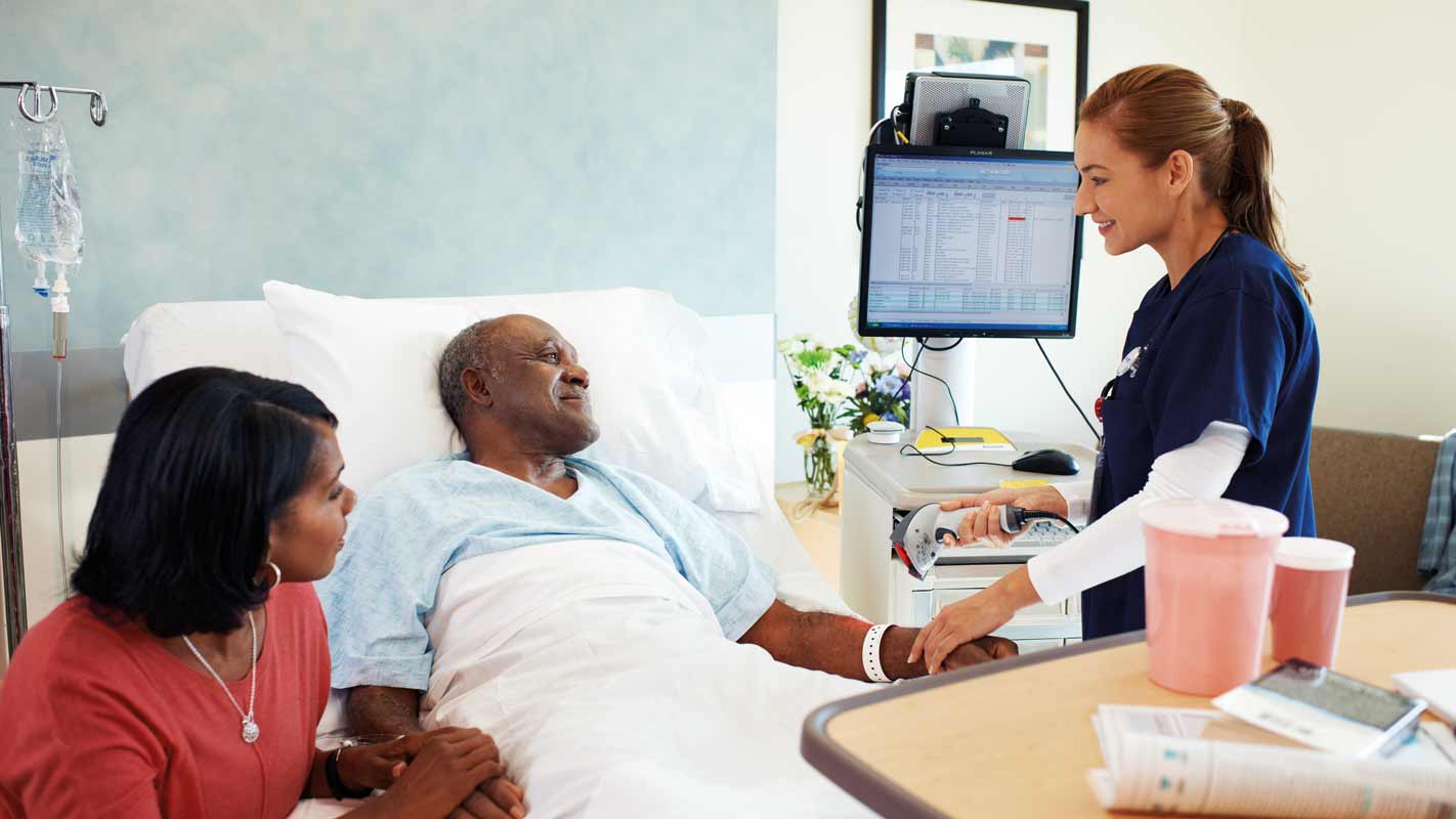 A nurse speaking to a patient lying in a hospital bed