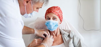 A doctor adjusts an IV for a cancer patient