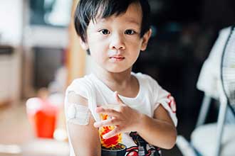 A child with a bandage on his arm after receiving a vaccine