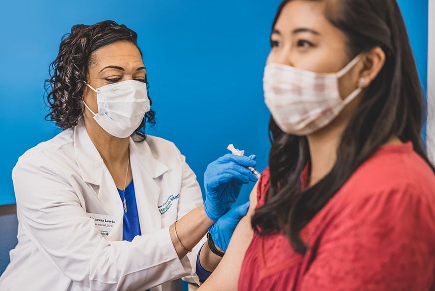 Healthmart pharmacist injecting patient with COVID vaccine