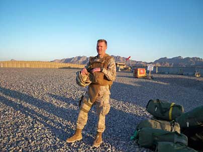 Jeff Oman dressed in military fatigues standing in a desert