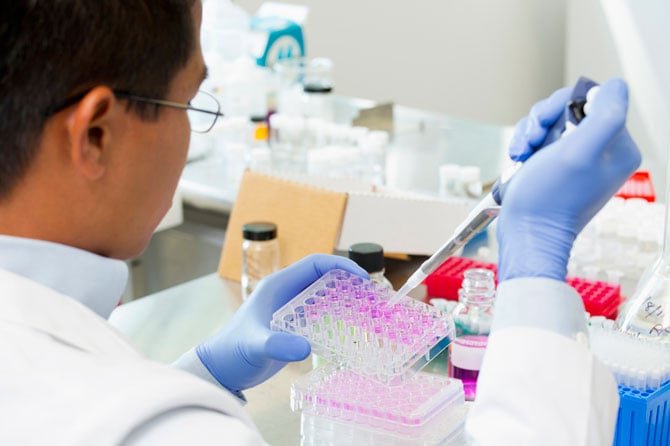 A doctor carefully filling vials with exact drops of a solution