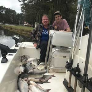 Terry Black and his teenage son on a fishing boat surrounded by fish and fishing supplies