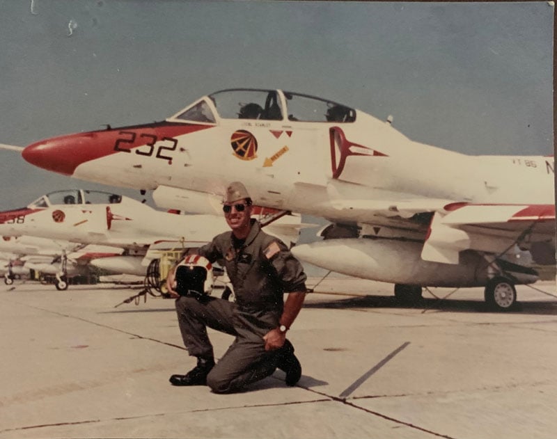 Paul McKeon kneeling in front of a fighter jet